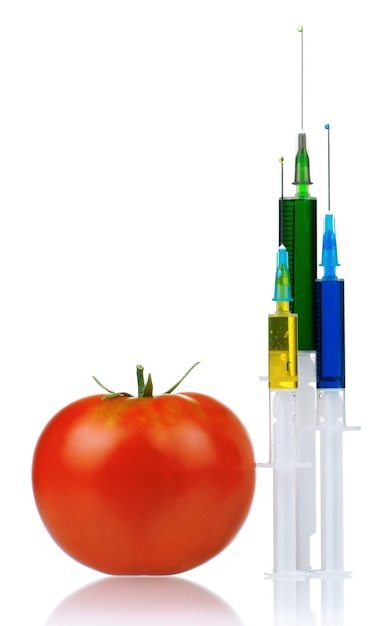 Foto tomato maturo di organismo geneticamente modificato con siringhe su sfondo bianco