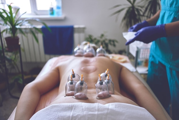 Genezing van bloedvergieten, hijama of aderlaten. Hajam-meester voert cupping-therapie uit op een jonge vrouw. islamitische geneeskunde