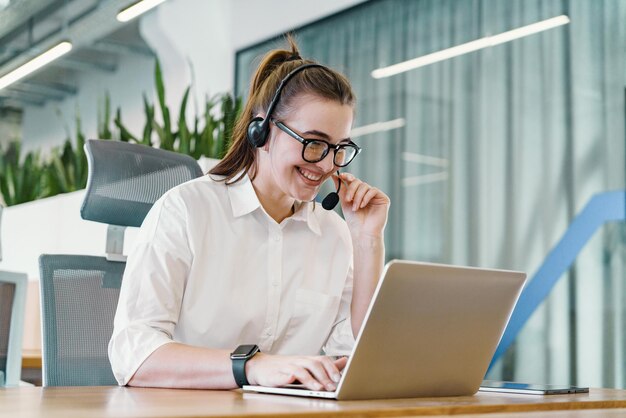 A genial customer support agent with a headset communicates cheerfully on a call while working