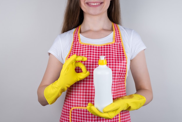 Geniet van een nieuw productvorm gecontroleerd bedrijfsconcept. Bijgesneden close-up foto van mooi meisje met fles met dispenser in handen die aanbeveelt om het geïsoleerde grijze achtergrond te gebruiken