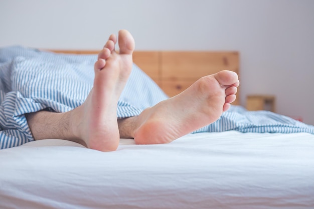 Genieten van de ochtend in bed Close-up van onbedekte vrouwelijke voeten in de beddeken