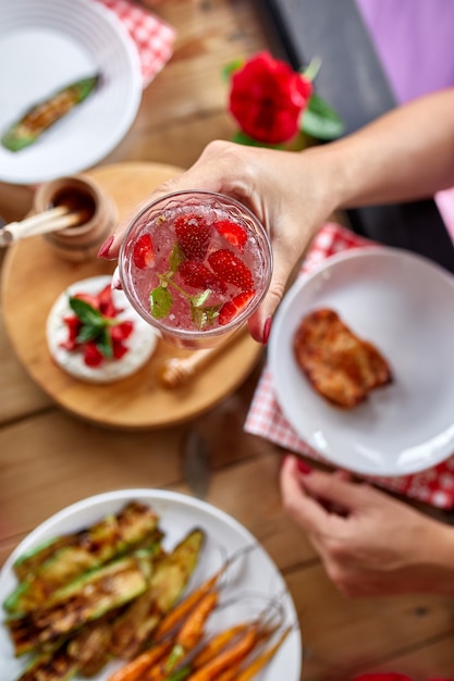 Genieten van diner vrouw eten, drinken limonade, eettafel, voorgerechten verscheidenheid serveren op partij buitentafel thuis.