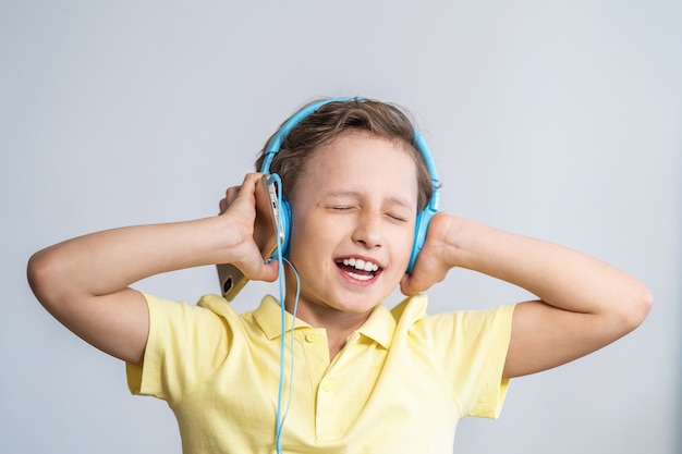 Genieten van het afspelen van liedjes in de koptelefoon. Kleine jongen zingt op lied, grote muziekfan.