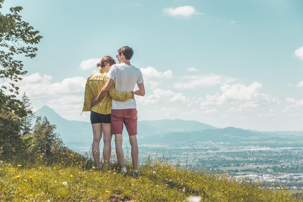 Genieten van het idyllische berglandschap Een stel staat op een idyllische weide en geniet van het uitzicht over de verre stad Salzburg