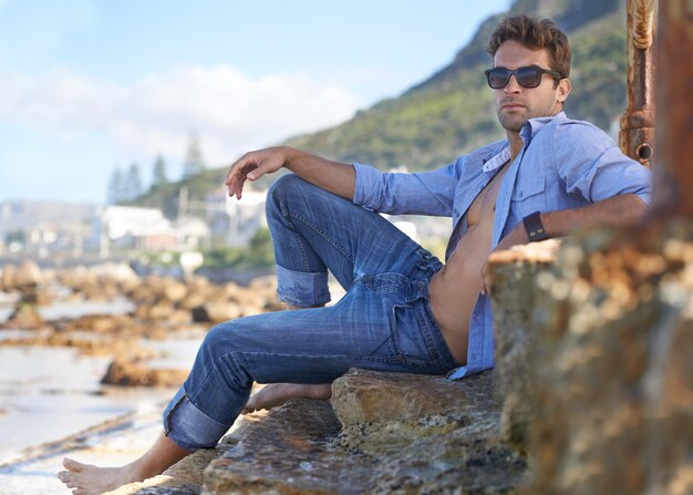 Genieten van het landschap Een jonge man die ontspant op het strand