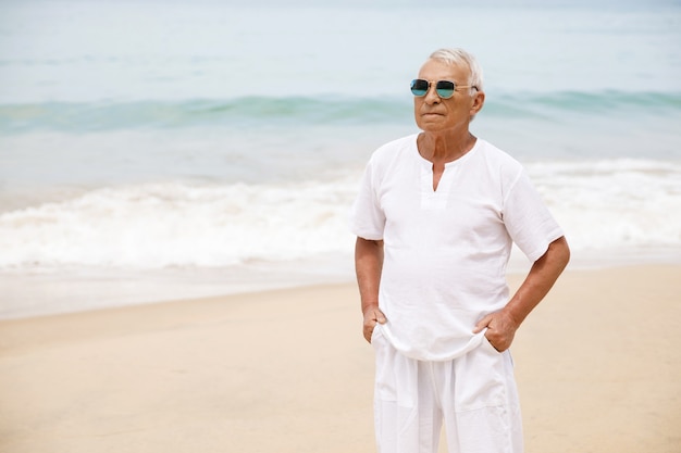 Genieten van het pensioen. Gelukkig senior man wandelen op het strand.