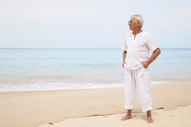 Genieten van het pensioen. Gelukkig senior man wandelen op het strand.