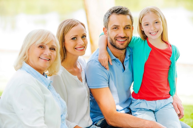 Genieten van tijd met familie. Gelukkige familie hecht zich aan elkaar en glimlacht terwijl ze samen buiten zitten