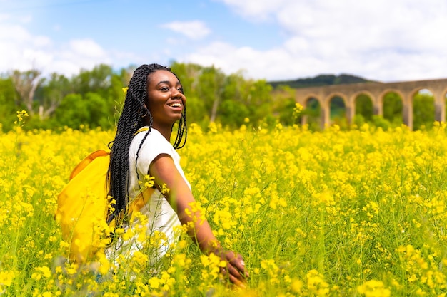 Genieten van vrijheid een zwart etnisch meisje met vlechten een reiziger in een veld met gele bloemen