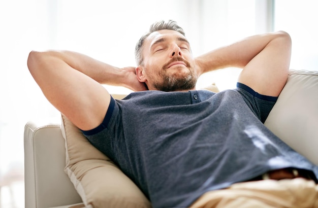 Genieten van zijn vrije dag Shot van een knappe volwassen man die thuis op de bank ontspant