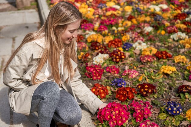 Genietend van de eerste bloemen van de lente raakt een jonge blanke vrouw zachtjes een bloem aan