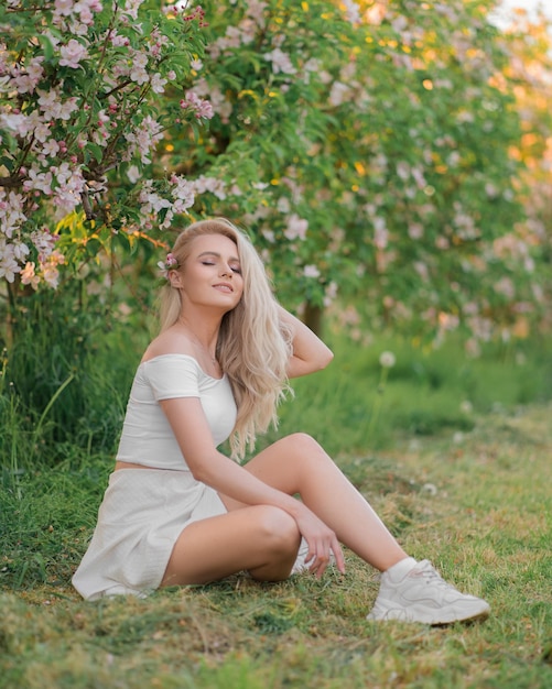 Gentle beautiful girl in white clothes among the apple orchard Apple tree flowers