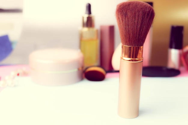 Gentle brush of natural lint for applying powder on the background of a cosmetic table for makeup