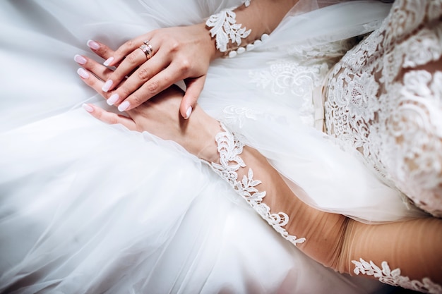 Le mani delicate della sposa tengono un abito da sposa.