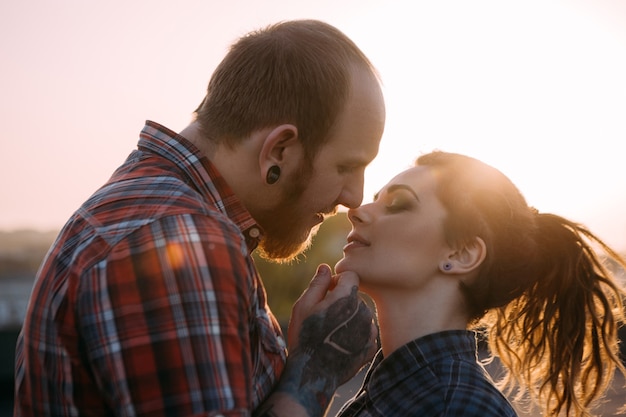 優しい流行に敏感なカップルのキス。青年関係の背景。優しい若者が一緒にクローズアップ、前景に焦点を当てた雰囲気のあるバックライト、愛の概念