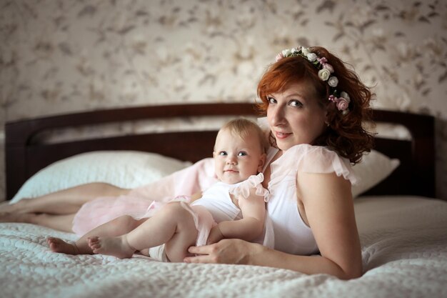 Photo gentle mother and daughter on the bed in a real room the concept of motherhood and affection