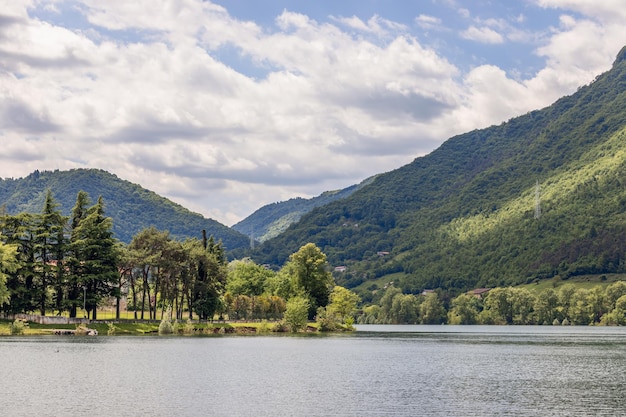 Dolce pendio di alta montagna incorniciato lago d'idro con alberi sempreverdi, brescia, lombardia, italia