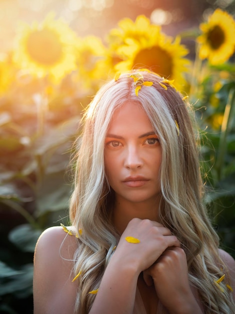 Gentle woman in petals of sunflower in field