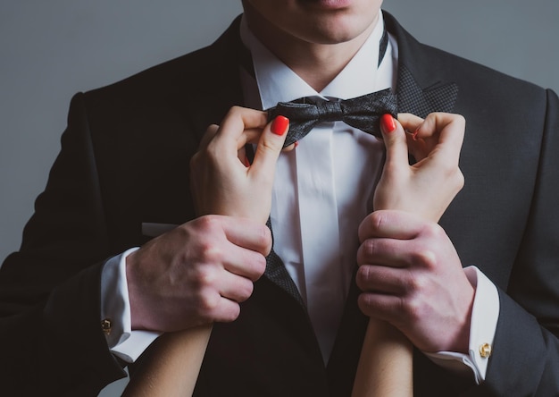 Foto le mani delle donne del vestito da gentiluomo raddrizzano la cravatta, il business della moda maschile sembra abiti eleganti ed eleganti