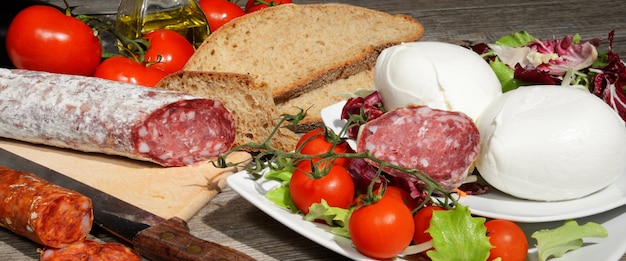 Photo genuine product salami, mozzarella, bread and little tomatoes