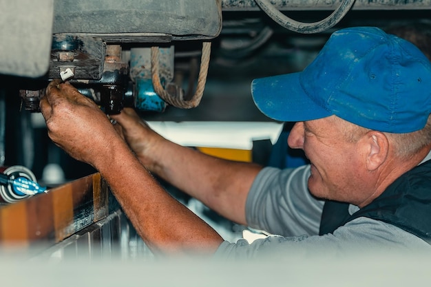 Genuine truck repair worker repairs machinery portrait of auto\
mechanic at work truck suspension repair