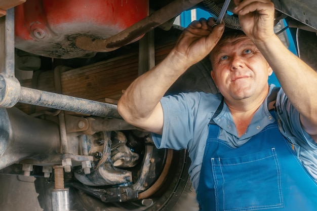 本物のトラック修理労働者は、機械を修理します 仕事中の自動車整備士の肖像 トラックのサスペンション修理