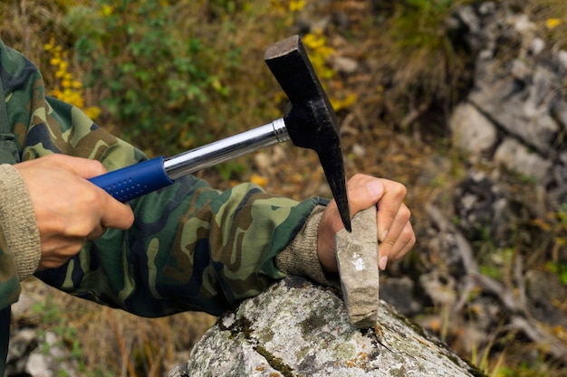Геолог исследует минералогический образец с помощью геологического молотка.