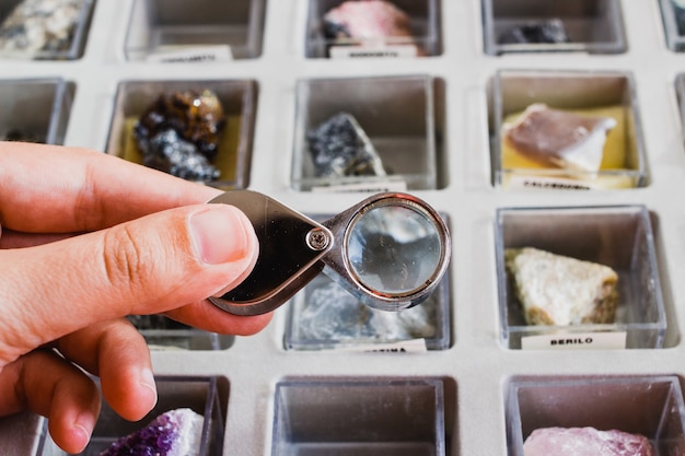 Photo geologist looking a collection of minerals with a magnifying glass