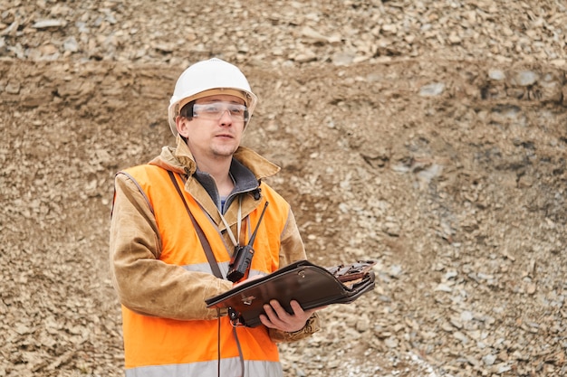 Foto geoloog of mijningenieur met zaktablet voor werkdocumentatie buiten op de mijnsite