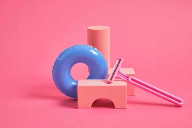 Geometric blowouts, pink disposable razors and small toy inflatable circle summer vacation and hair removal