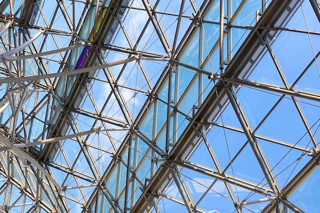 Geometric metal structure with glass ceiling in a shopping center against the sky