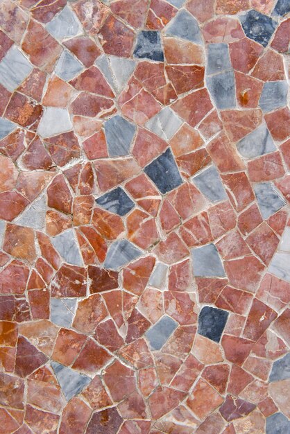 Geometric mosaic texture with multicolored tiles on floor made of red marble traditional mosaic