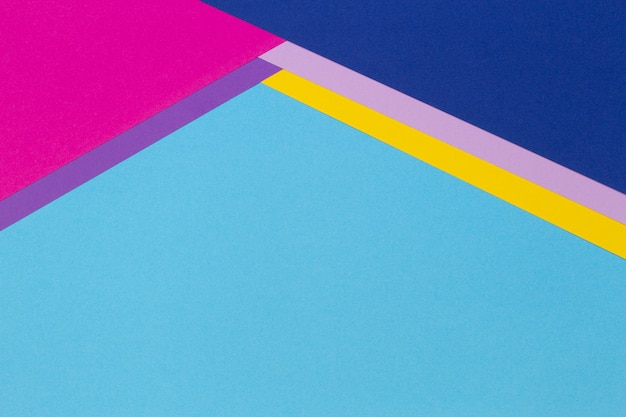 幾何学的な紙の背景に水色、黄色、ピンク、紫の色の紙