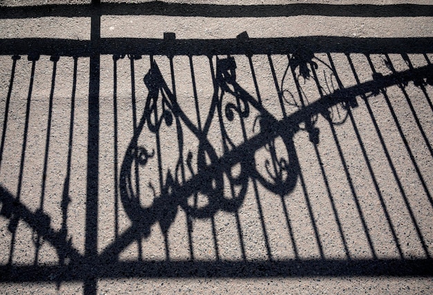 Geometric pattern fence shadow on sidewalk