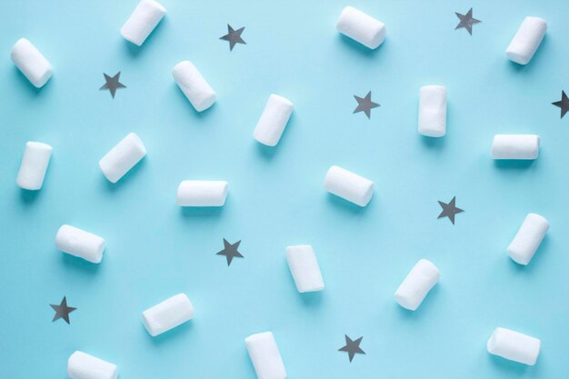 Geometric pattern of white marshmallows and stars on blue pastel background Food concept