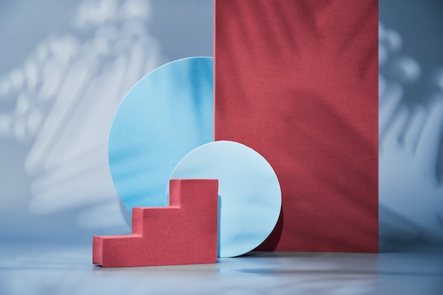 Geometric shapes on a blue wall, empty podiums for the presentation of various products, abstract geometric wall with a pedestal