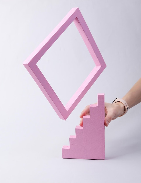 Geometric shapes minimalistic concept hand holds stairs and frame on gray background