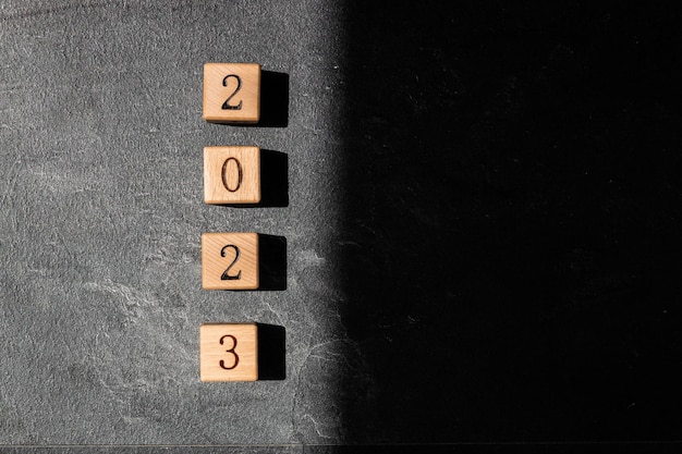 Geometric wood cubes on table with numbers 2023 Concept of new year 2023 copy space