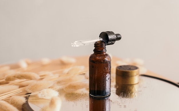 Foto geopend bruin glazen druppelflesje met een pipet met een zwarte rubberen punt met waterdruppels