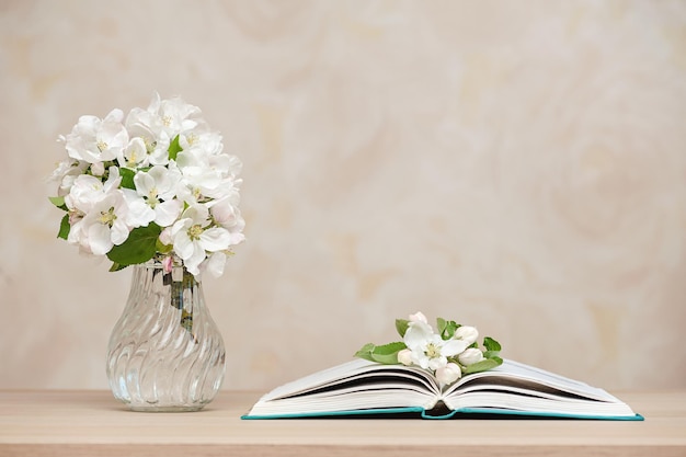 Geopende boeken en een vaas met witte bloemen op tafel tegen de achtergrond van de muur