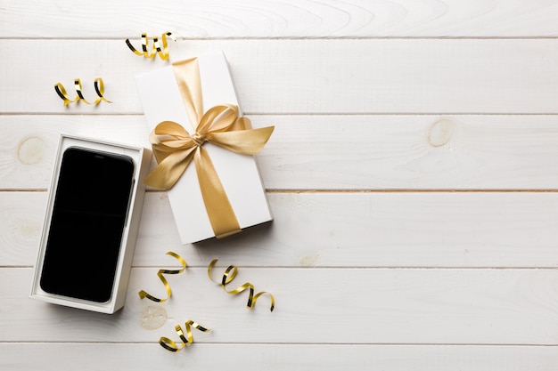 Geopende geschenkdoos met gouden lint en smartphone op kleur achtergrond bovenaanzicht Leeg open doos verpakkingsmodel sjabloon voor uw ontwerp branding mockup