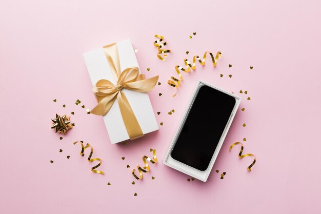 Geopende geschenkdoos met gouden lint en smartphone op kleur achtergrond bovenaanzicht Leeg open doos verpakkingsmodel sjabloon voor uw ontwerp branding mockup