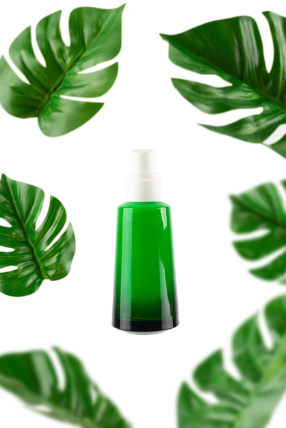 Geopende groene fles met tropisch monsterablad op geïsoleerde witte close-up als achtergrond