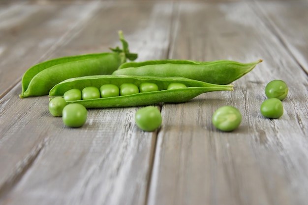 Geopende peulen van verse groene erwten op houten achtergrond