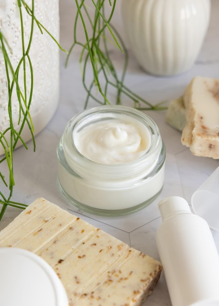 Geopende room pot met witte lege deksel op marmer bij groene plant close-up cosmetische mockup