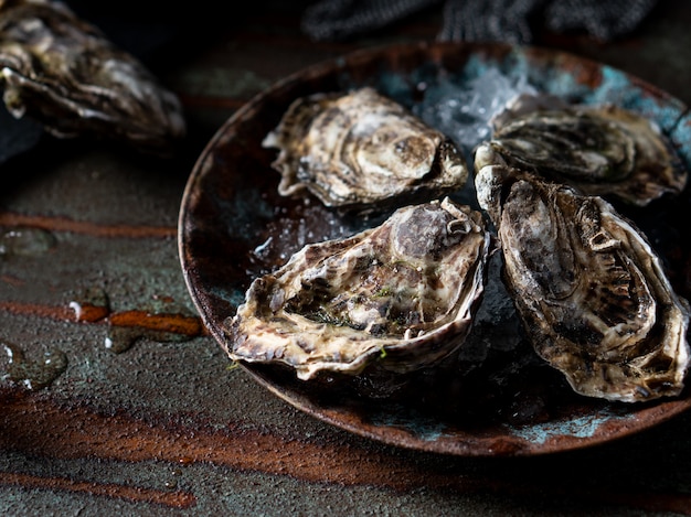 Geopende verse oesters op een donkere achtergrond, een mes en waterdruppels. Rostik stijl.