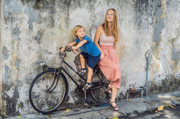 ジョージタウン、ペナン、マレーシア-2018年4月20日：自転車に乗った母と息子。公共のストリートアート名前ジョージで自転車に乗っている2人の小さな中国人の女の子が壁に3Dで描かれた自転車の子供たち
