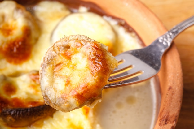 Georgian cuisine: Close up mushrooms baked with cheese suluguni on ketsi