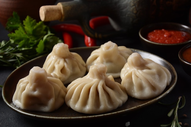 Georgian dumplings Khinkali with meat and red pepper, Traditional National Georgian cuisine. Khinkali with   local sauces - tkemali, satsebeli, adzhika.