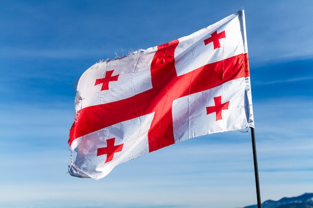 Georgian flag waving in the wind on the surfce of blue, clear sky